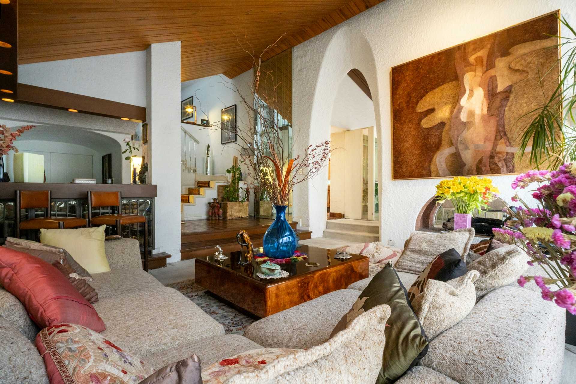 Living room with warm neutral sofas, wood furniture, and arched wall details.