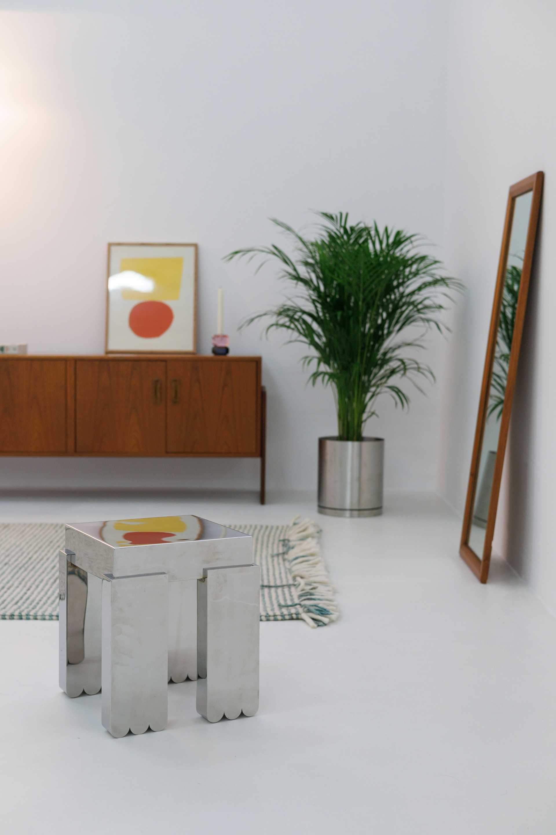 Light room with vintage wood furniture, sculptural seating, and a plant.