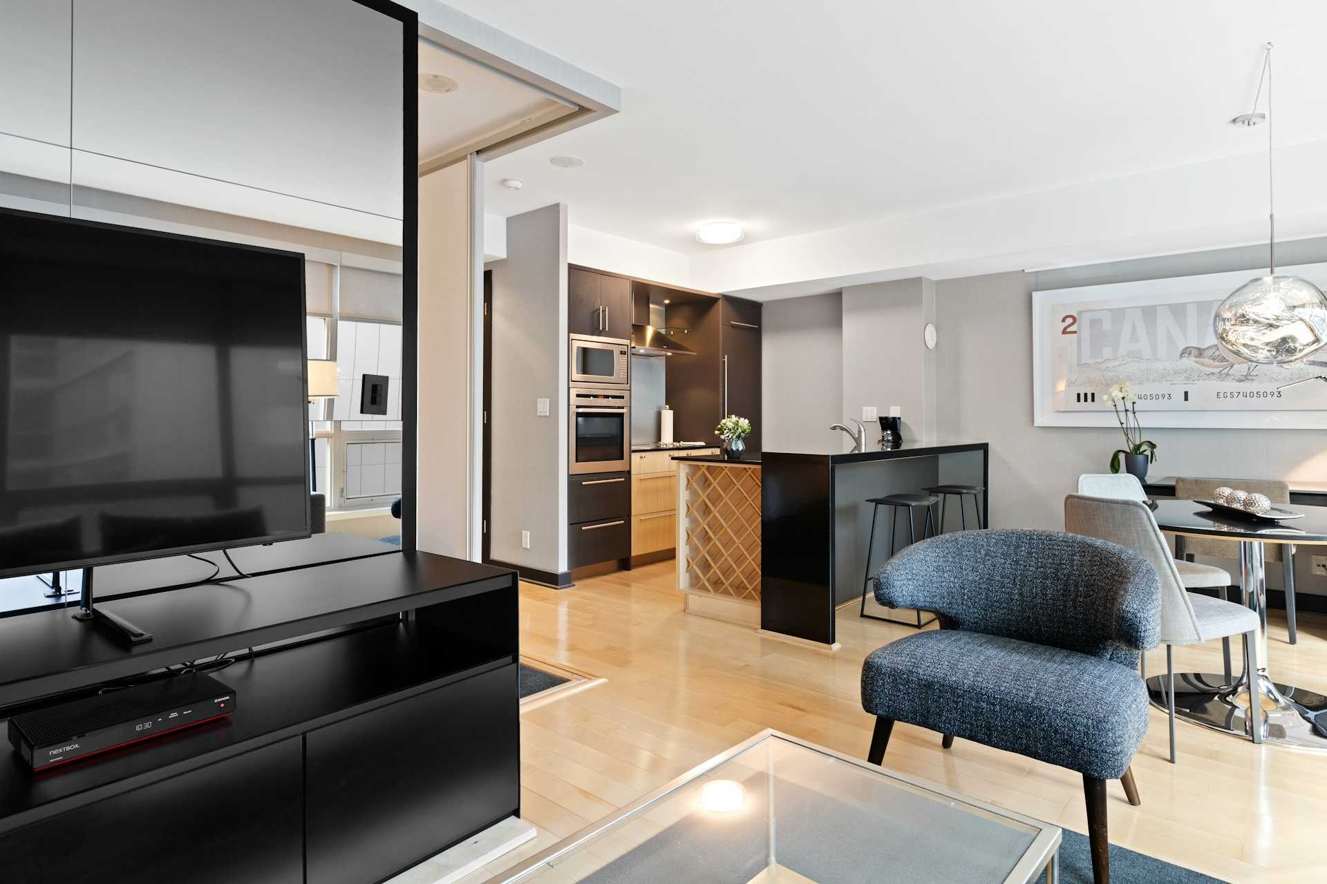 Open living area beside a kitchen with wood cabinets and a dark island.