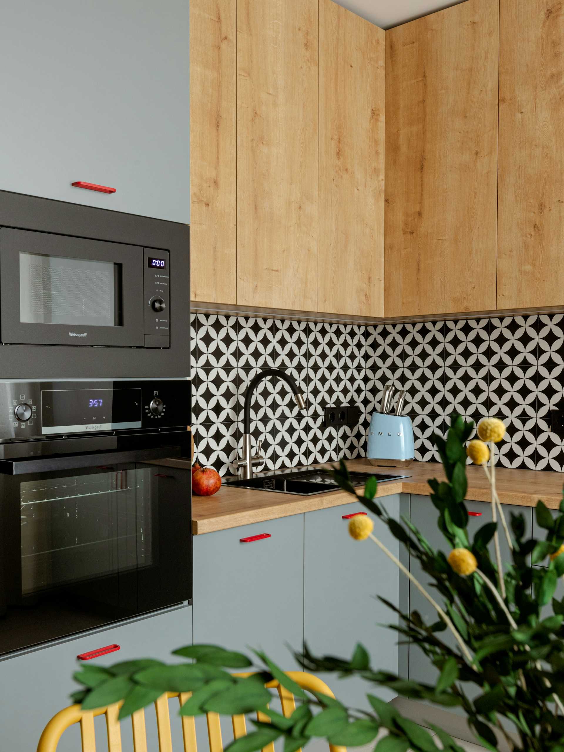 Light wood cabinet doors beside gray cabinetry and a patterned backsplash.
