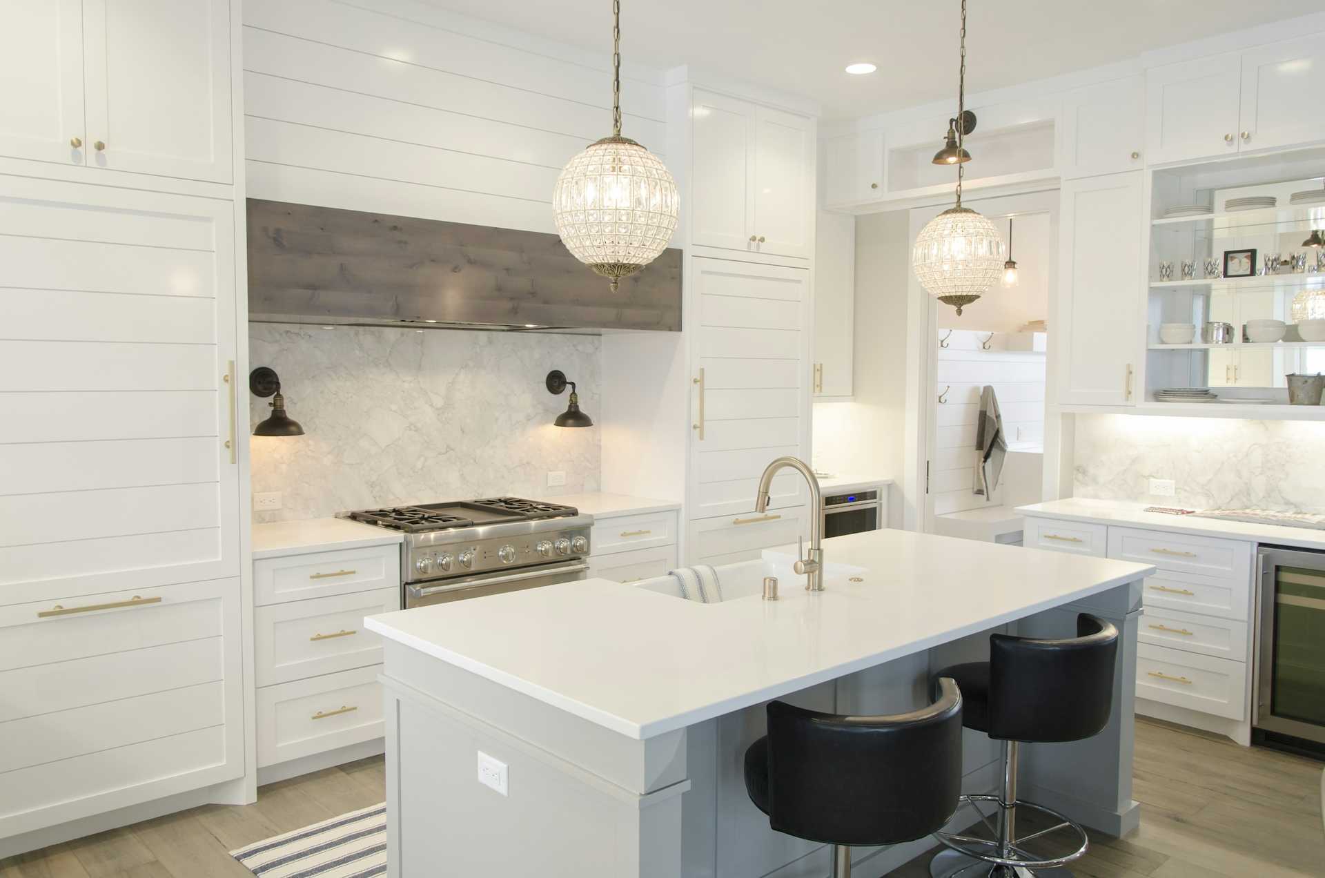 White framed cabinets, an island, and globe pendants in a bright kitchen.